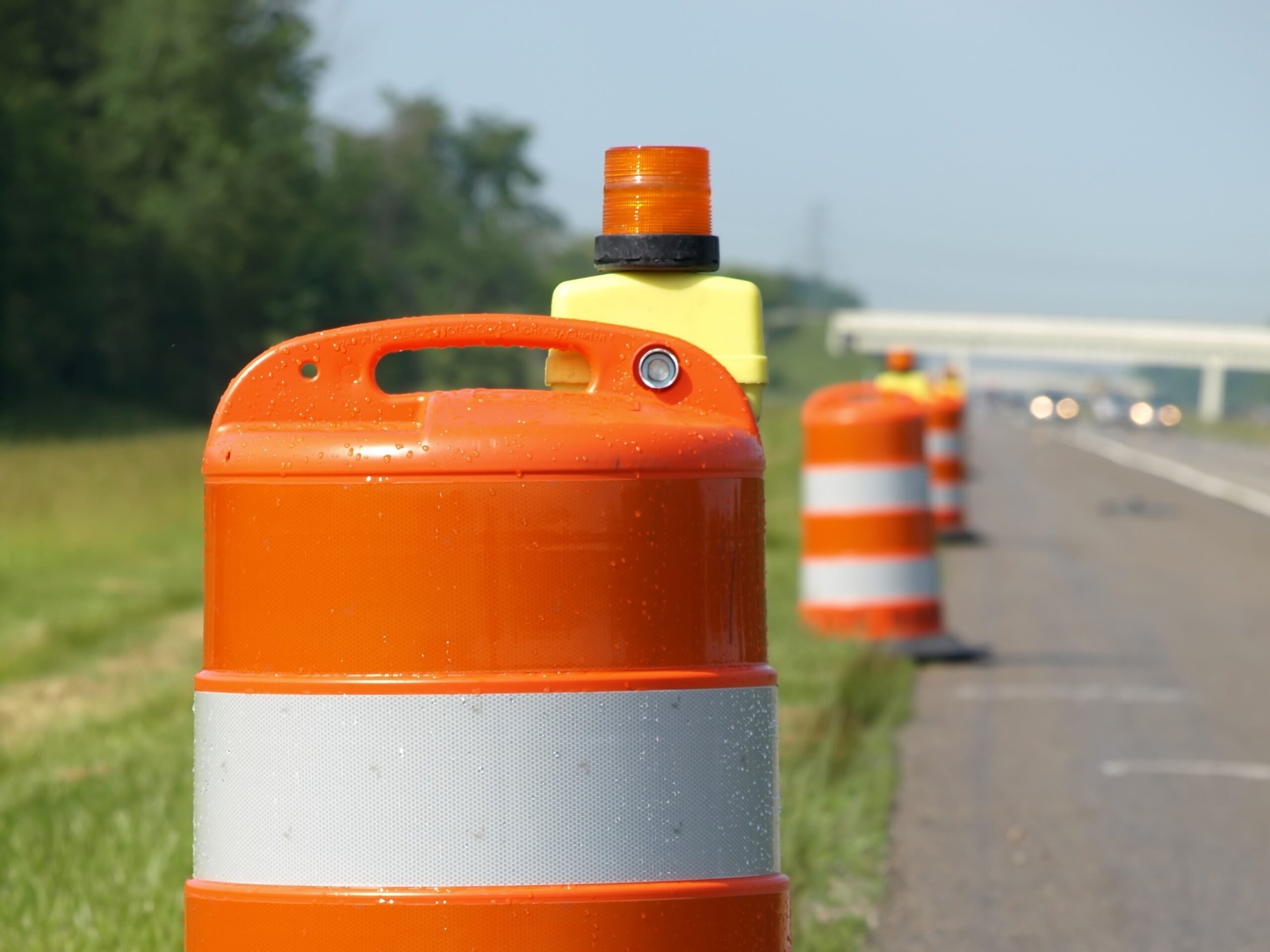 Orange and white construction barrels along highway